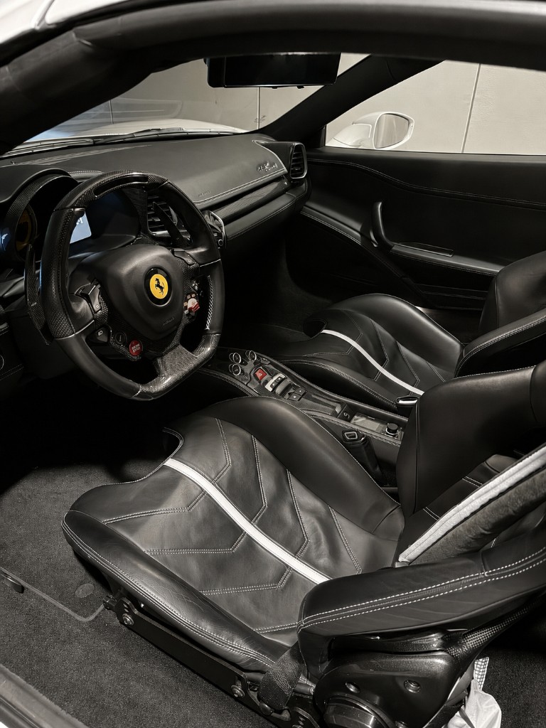 法拉利 458 Speciale 黑色真皮內裝與白色對比縫線、碳纖維飾板,座椅與方向盤呈自然霧面質感,象徵健康皮革狀態