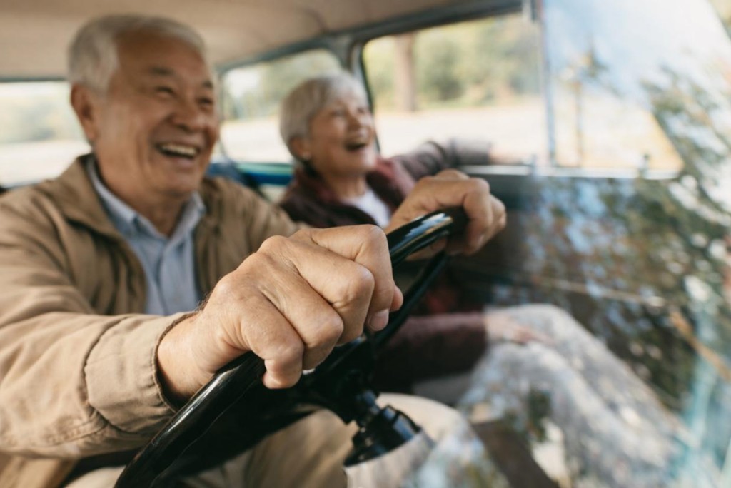 銀髮伴侶日間開車出遊,手握方向盤、車內溫馨笑語的休閒用車情境