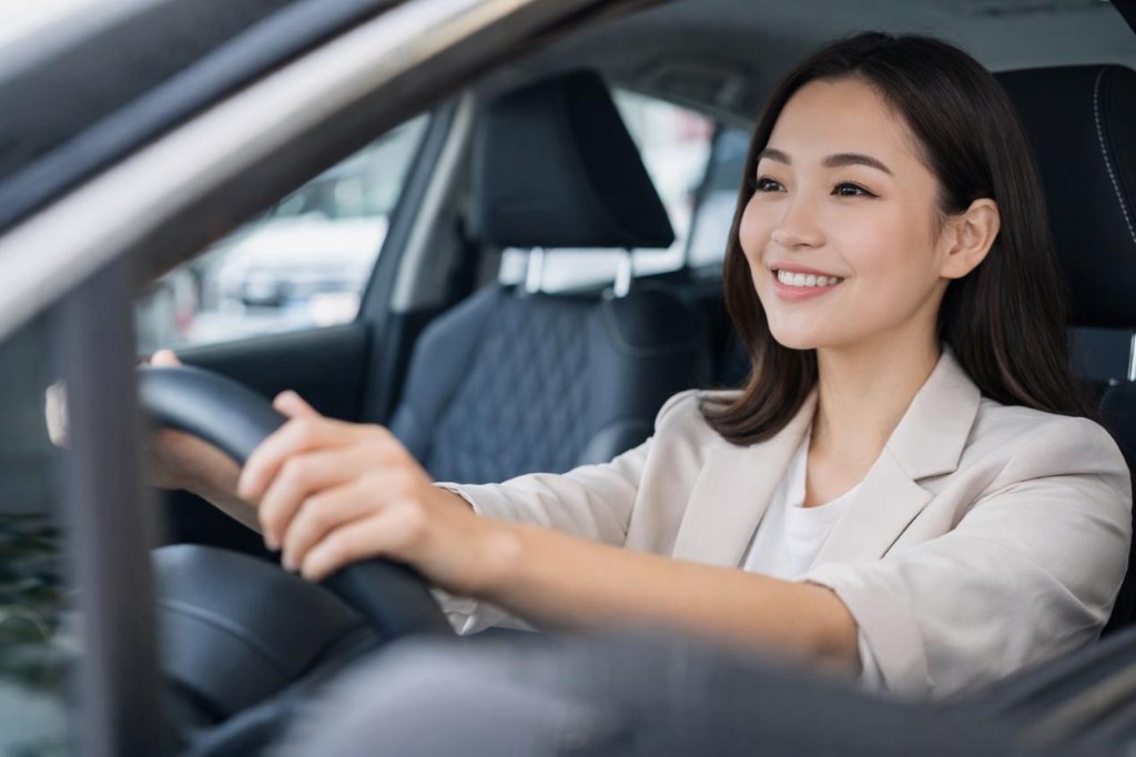 女性駕駛於現代車內雙手握持方向盤、微笑前行,象徵高頻通勤與對穩定用車的重視